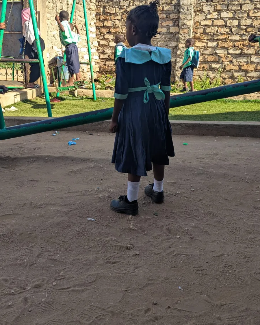 Una alumna con uniforme en el patio de la escuela, de espaldas